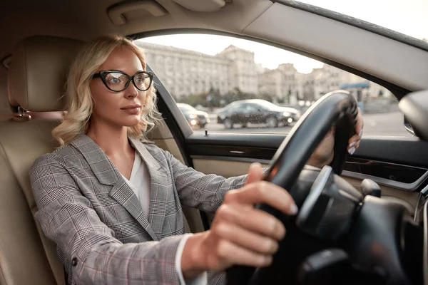 A caminho do escritório. Retrato de mulher de negócios atraente em elegante desgaste clássico dirigindo um carro — Fotografia de Stock