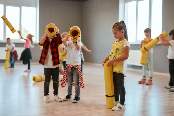 Mi diverto. Due ragazzini in abiti casual con in mano dei tappetini gialli da yoga mentre erano in sala da ballo. I bambini vanno a fare esercizi di stretching — Foto Stock