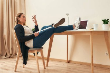 Rahat bir iş yeri. Kablosuz kulaklık takan kadın iç mimar ya da mimarın yan görünüşü ve evden çalışırken birisiyle yeni inşaat projesini tartışmak