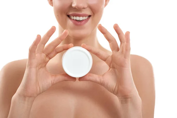 I love this cream. Young attractive woman demonstrating cosmetic product and smiling at camera while standing against white background. — Stock Photo, Image