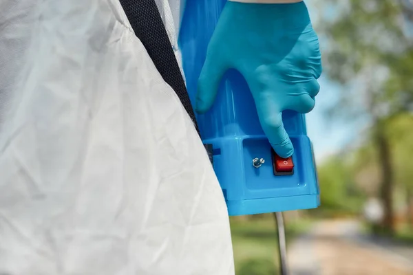 Βάλε τα δυνατά σου. Κοντινό πλάνο του χεριού του εργαζομένου πατώντας κουμπί διακόπτη σε ηλεκτροστατικό ψεκαστήρα σακίδιο. Καθαρισμός στους δρόμους με σακίδιο με νερό απολυμαντικό σπρέι υπό πίεση — Φωτογραφία Αρχείου