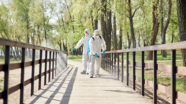 Żadnych zarazków. Sanityzacja, czyszczenie i dezynfekcja parku miejskiego w związku z pojawieniem się wirusa Covid19. Specjalistyczny zespół w kombinezonach ochronnych i maskach w pracy — Zdjęcie stockowe