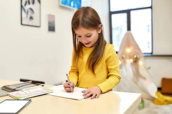 Bebé con una sonrisa brillante. Caucásico linda niña dibujo mientras la niñera haciendo el almuerzo. Educación infantil, actividades de ocio, concepto de cuidado de niños —  Fotos de Stock