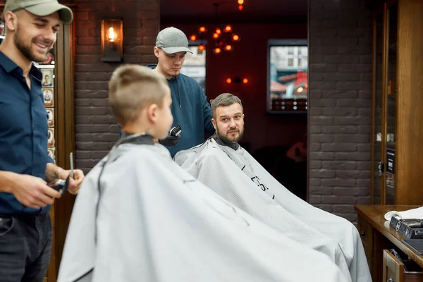 Jour de famille. Jeune père et son petit fils visitant salon de coiffure, faire des coupes de cheveux ensemble — Photo