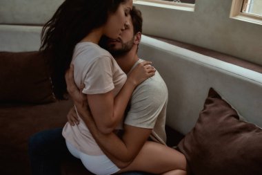 Yaklaş. Genç ve seksi kadın kanepede sevişmeden önce sarılıyorlar.