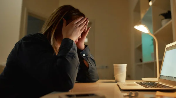 Me siento agotado. Mujer joven cansada mirando la pantalla del ordenador portátil, sentada en su lugar de trabajo por la noche en casa. Trabajando remotamente, desde casa —  Fotos de Stock
