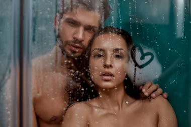 Islak ve romantik. Genç çıplak çift duş kabininde dinleniyor.