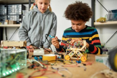 Evet, yapabiliriz. Çocuk çip ve telleri birleştirmek için lehimleme demiri kullanıyor. Sürece bakan arkadaşı. İlkokul öğrencileri için robotik ve yazılım mühendisliği. Çocuklar için icatlar ve yaratıcılık