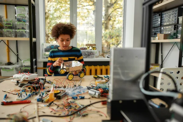 Calidad en cada trabajo. Niño usando destornillador mientras fija pernos en un vehículo robot. Niños inteligentes y educación STEM . — Foto de Stock