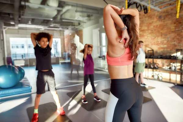 Un posto per energizzarti. Ritratto di allenatrice che si scalda, si allena con adolescenti, ragazzi e ragazze in palestra. Stretching in una giornata di sole. Sport, stile di vita sano, educazione fisica — Foto Stock