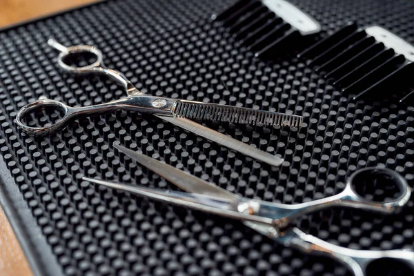 Makas fotoğrafını kapat, berber dükkanında lastik bir paspasın üzerinde saç makası için iki hortum var.