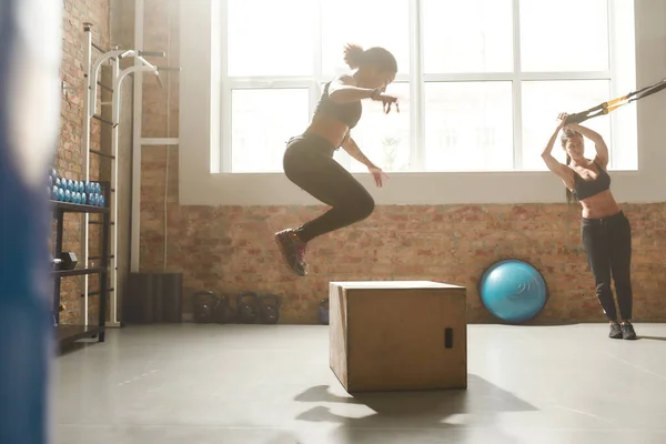 Viver melhor com fitness. Mulher esportiva pulando usando caixa de plyo ao ter treino no ginásio industrial — Fotografia de Stock