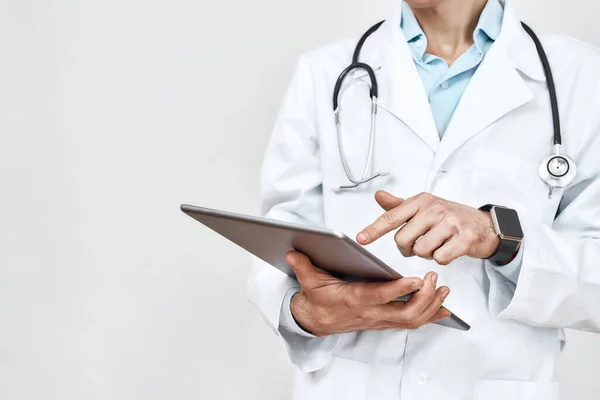 Medical consulting. Cropped photo of a male doctor in medical uniform with stethoscope around neck using digital tablet, standing against grey background — Stock Photo, Image