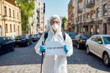 Dur ve düşün. Covid19 virüsünün ortaya çıkması nedeniyle şehrin sokaklarının temizlenmesi ve dezenfekte edilmesi. Koruyucu giysili ve maskeli bir işçi üzerinde 