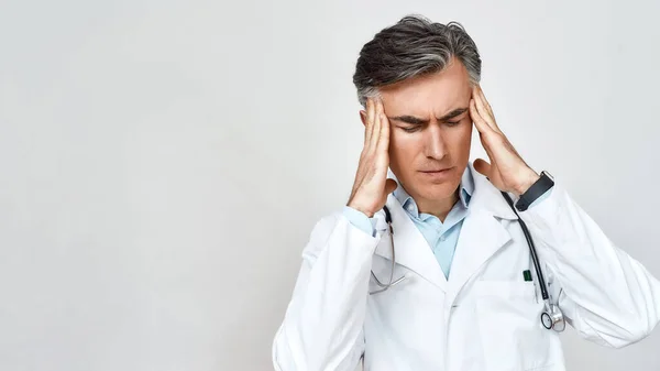 Πορτρέτο του δυστυχισμένου στρεσαρισμένο αρσενικό γιατρό στην ιατρική ομοιόμορφη αίσθημα κατάθλιψης, αγγίζοντας το κεφάλι με τα χέρια, ενώ στέκεται πάνω από γκρι φόντο — Φωτογραφία Αρχείου