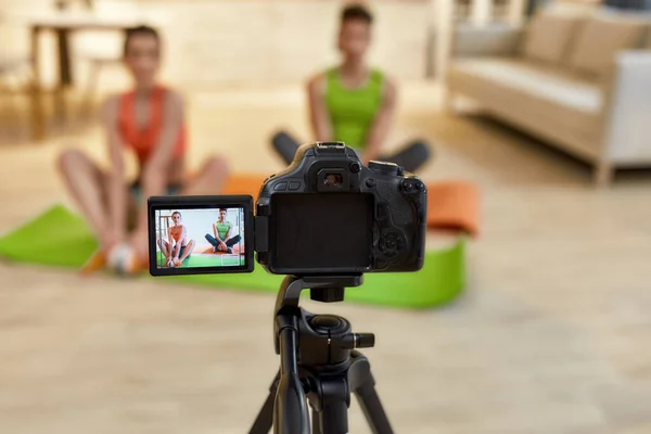Geschichten schreiben. Veränderungen herbeiführen. Junges Paar in Sportbekleidung nimmt Videoblog oder Vlog über gesunden Lebensstil vor der Kamera auf, während es zu Hause Yoga macht. Fitness, Workout und Vlogging-Konzept — Stockfoto
