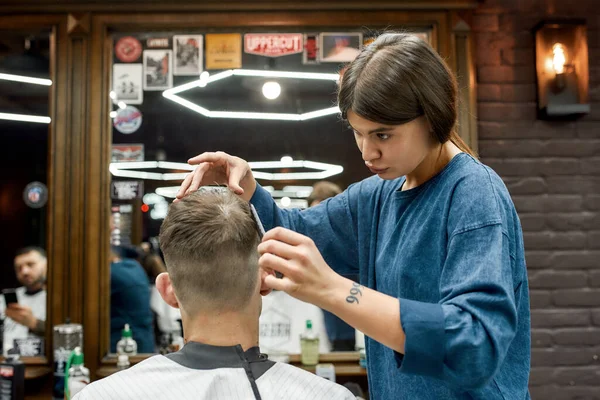 Bonito peinado. Joven hombre caucásico conseguir nuevo corte de pelo en la barbería moderna. Peluquera profesional haciendo corte de pelo para su cliente. Salón de belleza —  Fotos de Stock