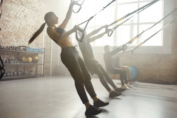 Σχηματίστε το. Πλήρες πλάνο των ανδρών και των γυναικών που κάνουν ασκήσεις γυμναστικής TRX στο βιομηχανικό γυμναστήριο. Push-up, ομαδική προπόνηση — Φωτογραφία Αρχείου