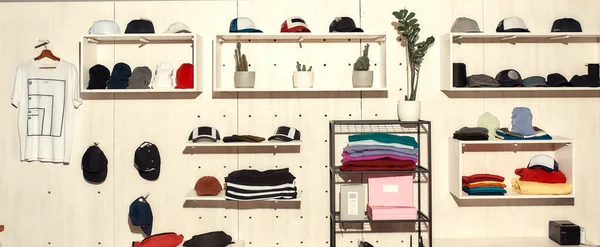 Limitless solutions. Custom apparel, clothes neatly arranged or folded on shelves. Stack of colorful clothing and baseball caps in the store