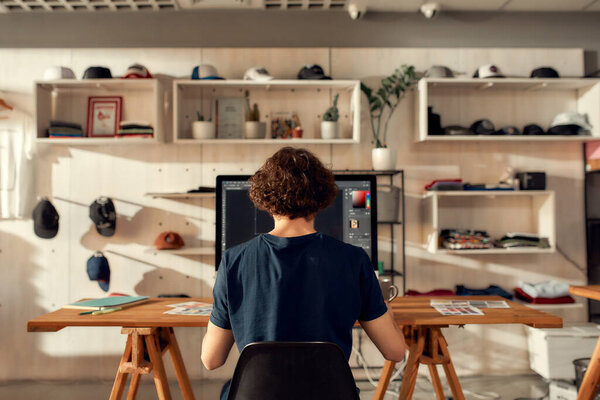 Excellence in graphic. Portrait of male worker sitting by desk, drawing sketches logo design using pc. Young man working at custom T-shirt, clothing printing company — Stock Photo, Image