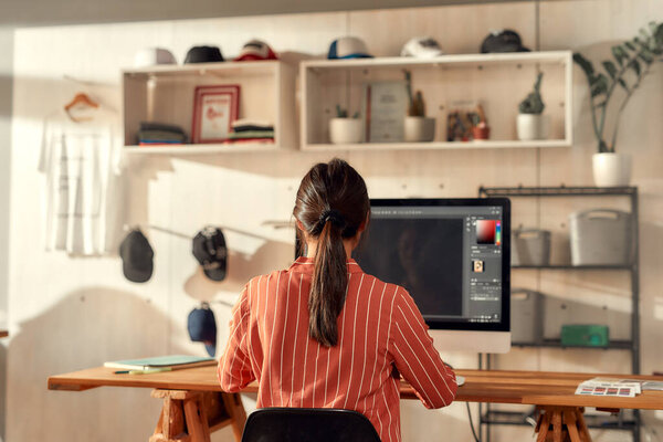 Taking ideas seriously. Portrait of female worker sitting by desk, drawing sketches logo design using pc. Young woman working at custom T-shirt, clothing printing company — Stock Photo, Image