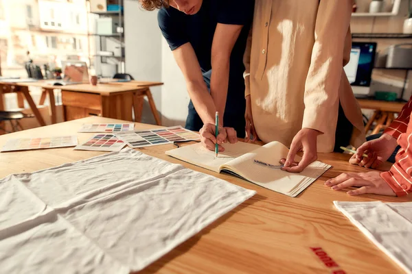 A nyomdászok. Vágott lövés tervezők rajz vázlatok, miközben létrehozva logó és design póló. Fiatal férfi és nő dolgozik együtt egyéni póló, ruházati nyomda — Stock Fotó