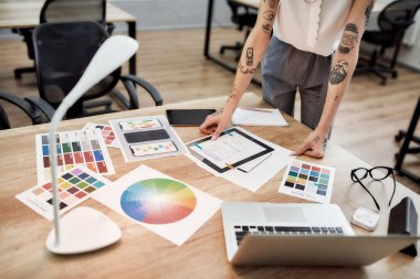 Grafik tasarımcısı iş başında. Ofis masasının yanında dururken yeni bir proje üzerinde çalışan dövmeli kadın tasarımcı görüşü. Renk örnekleriyle çalışmak