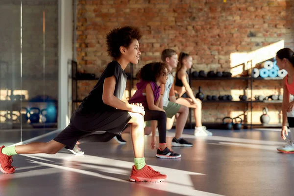 Make your commitment. Portrait of a boy smiling while warming up, exercising together with other kids and female trainer in gym. Sport, healthy lifestyle, physical education concept — Stock Photo, Image