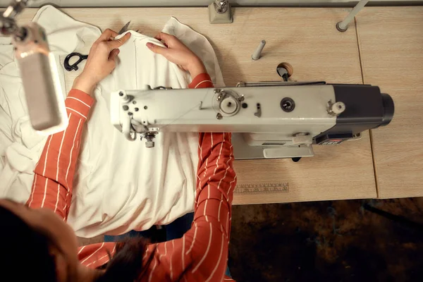 Radost z procesu. Pohled shora na švadleny sedící a šicí. Švadlena pracuje na šicím stroji. Krejčí na svém pracovišti vyrábí oděv — Stock fotografie