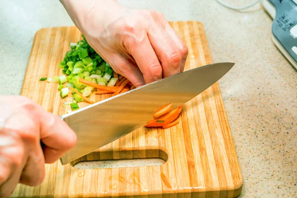 Female hand with knife cuts the carrot — Stock Photo, Image