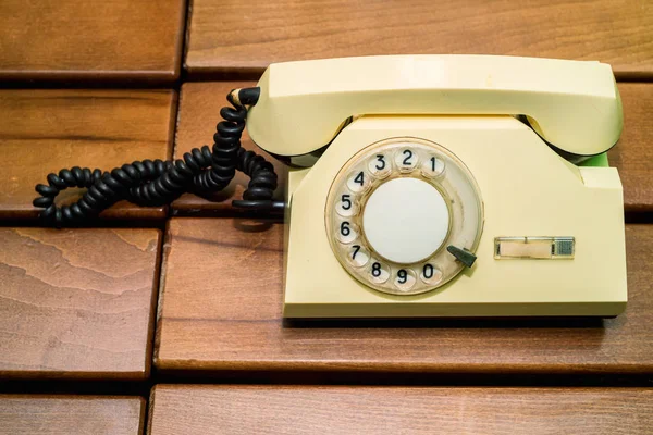 Velho telefone de disco bege no fundo de madeira — Fotografia de Stock