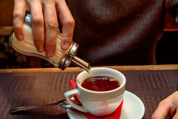 Рука кладет сахар в чашку с чаем — стоковое фото