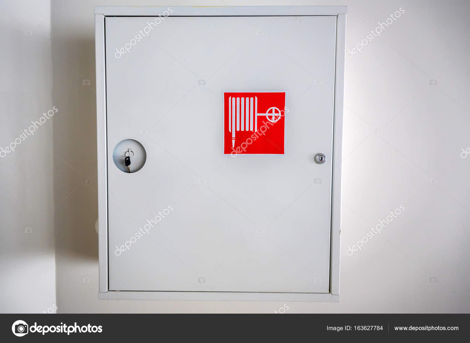 Weißer Schrank für Feuerhydranten an der Wand - Stockfotografie