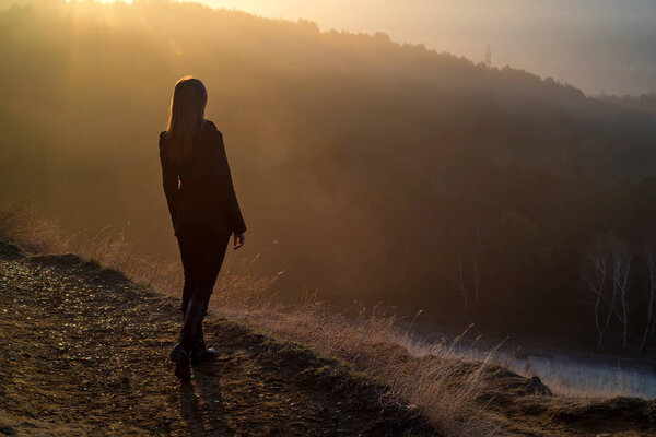 Female hiker standing on edge of rock at sunrise
