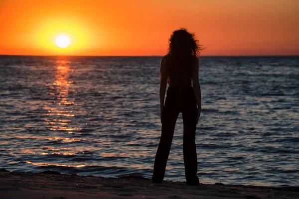 Силуэт молодой женщины на пляже на закате — стоковое фото