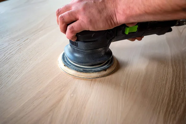 Hombre lijando madera con lijadora orbital en un taller — Foto de Stock