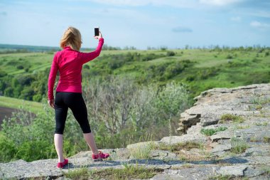 Kaya'nın kenarında duran kadın uzun yürüyüşe çıkan kimse