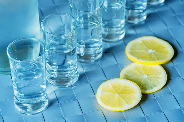 Vodka tiro de vidro e limão na superfície azul — Fotografia de Stock