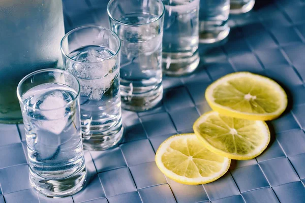 Vodka tiro de vidro e limão na superfície azul — Fotografia de Stock