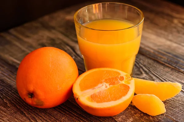 Naranjas y zumo de naranja sobre fondo de madera —  Fotos de Stock