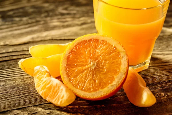 Oranges and orange juice on a wooden background — Stock Photo, Image