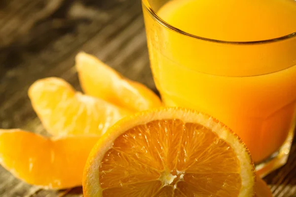Naranjas y zumo de naranja sobre fondo de madera —  Fotos de Stock