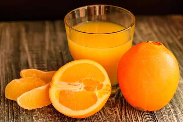 Naranjas y zumo de naranja sobre fondo de madera —  Fotos de Stock