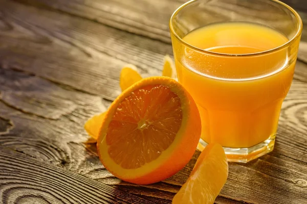 Naranjas y zumo de naranja sobre fondo de madera —  Fotos de Stock