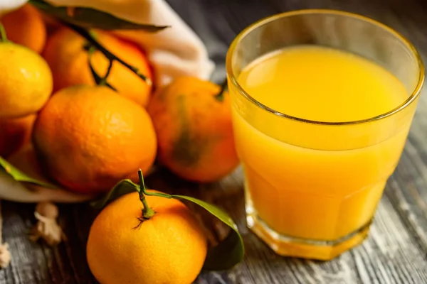 Vaso de jugo fresco y mandarinas en la mesa —  Fotos de Stock