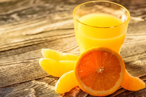 Naranjas y zumo de naranja sobre fondo de madera — Foto de Stock