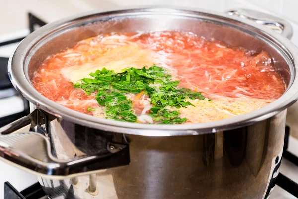 Adding chopped greens to vegetable soup — Stock Photo, Image