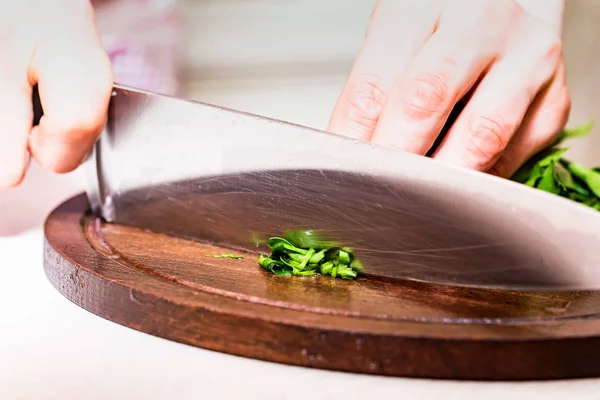 Female hands chopping herbs on wooden board — Stock Photo, Image