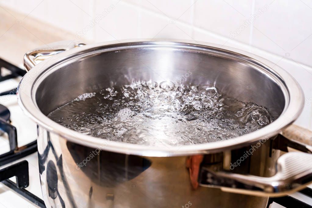 Boiling water for soup in modern saucepan