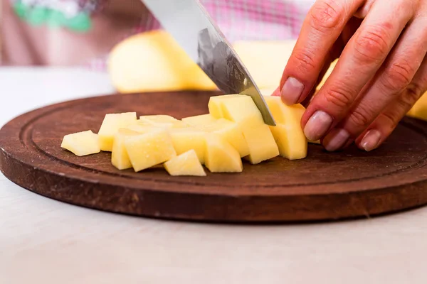 Female hands cut potatoes on wooden board — Stock Photo, Image